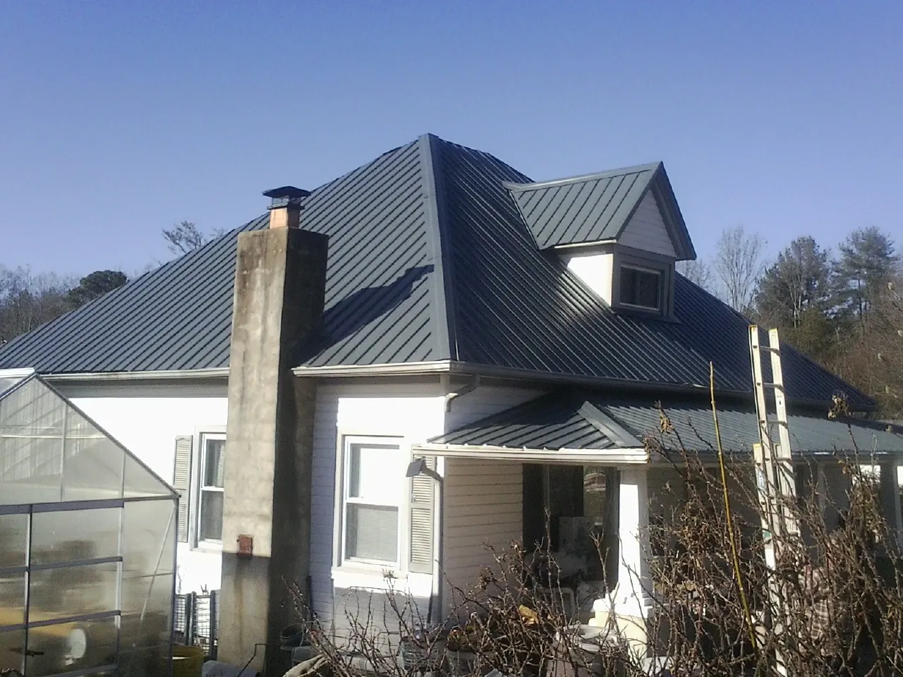 Dark blue standing seam metal roof on a white farmhouse with dormer — Slate & Tile Roof Repair by Roofing Brothers in Campo
