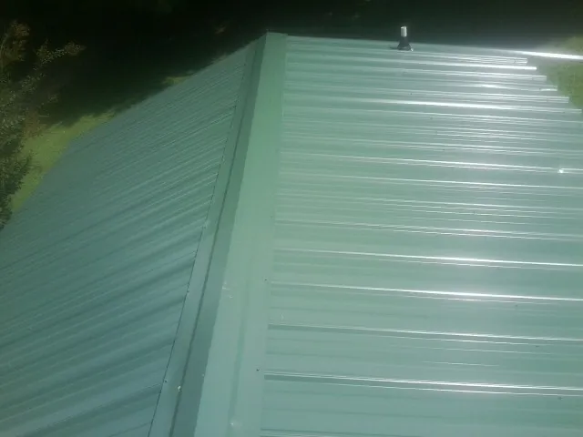 New green metal panels meeting at the ridge of a roof — Flat Roof Repair work by our crew in Campo