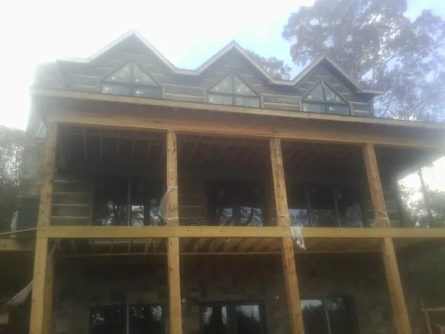 Dormers and porch framing on a large log home under construction — Roof Coating work by our crew in Campo