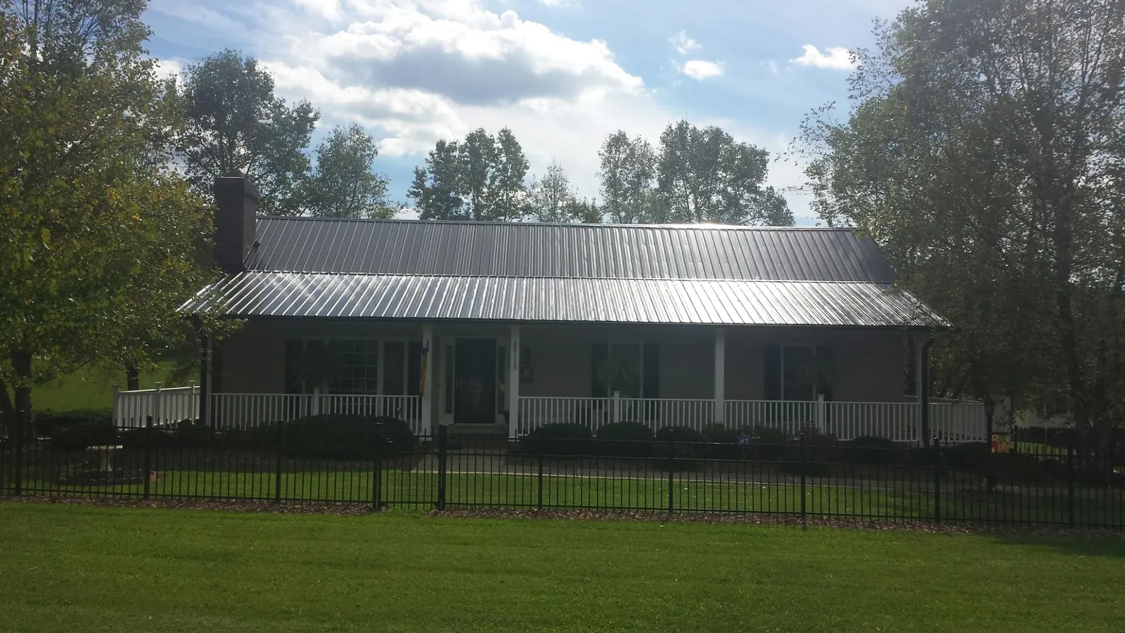 Gray metal roof on a brick ranch with a full width front porch — Gutter Guard Installation work by our crew in Campo