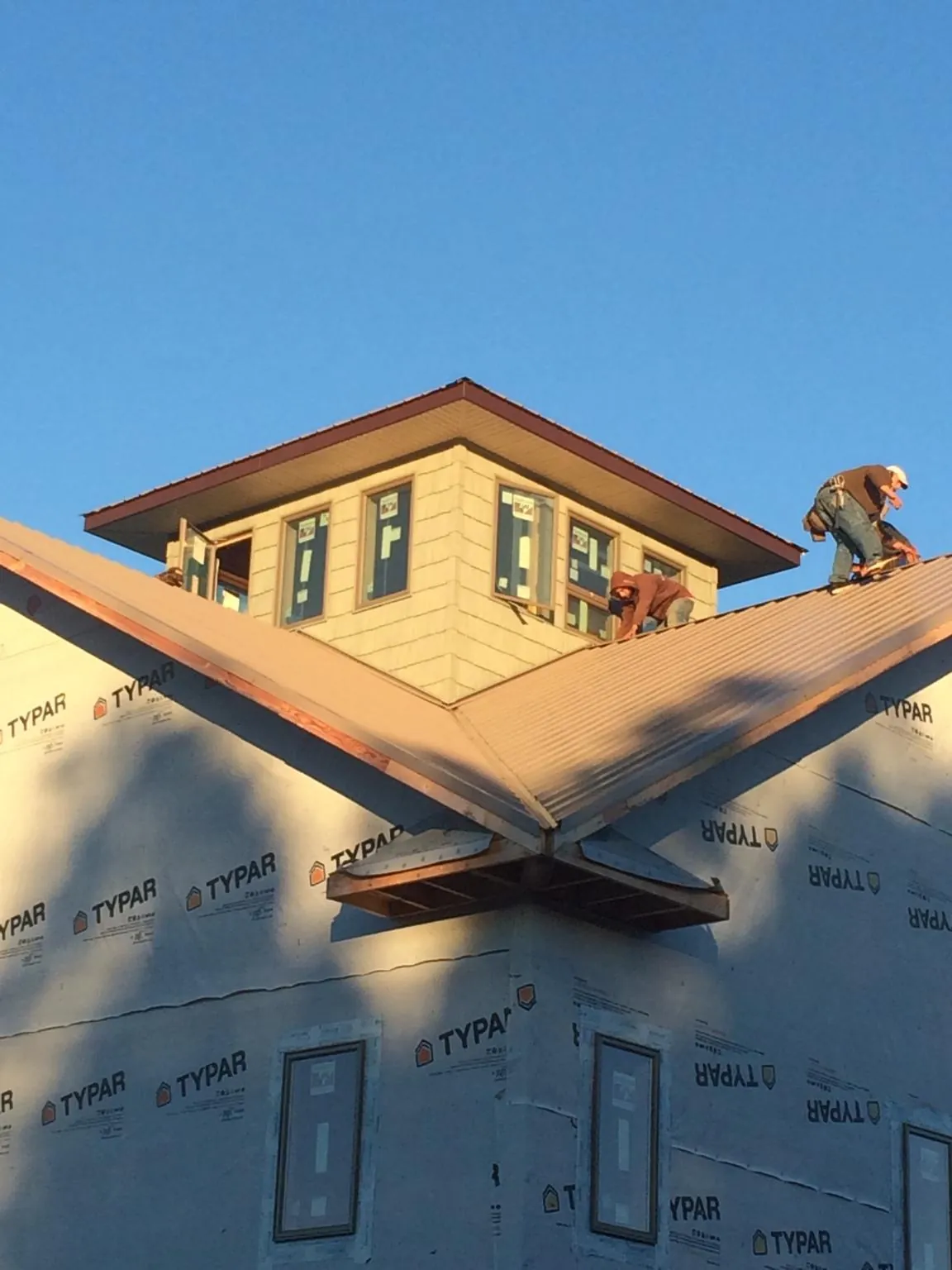 Roofers working around a rooftop cupola on a new metal roof at sunset — Roof Waterproofing in Campo by Roofing Brothers